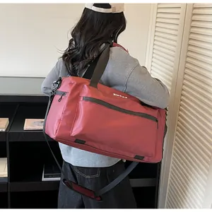 Detailed view of large burgundy travel bag worn by model in a casual lifestyle scene