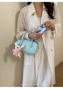 Detail shot of a minimalist light blue bowling bag with a cute rabbit doll charm