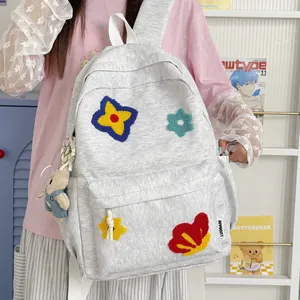 Grey cute student backpack with colorful embroidered flower patches held by a person
