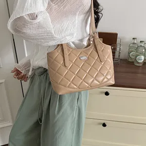 Elegante beige gesteppte Tragetasche in einem Lifestyle-Ambiente mit weißer Bluse und grüner Hose