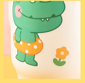 Macro view of cute green dinosaur and yellow flower waterproof stickers on white cup