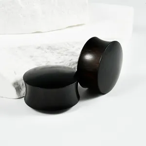Detailed macro view of solid ebony wood double-flared ear plugs on textured white stone blocks