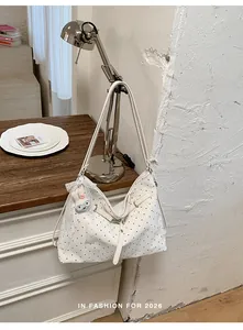 White polka dot tote bag with cute bunny charm hanging on a desk lamp detail view