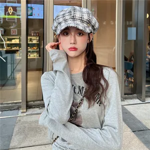 Detail shot of a black and white plaid newsboy cap worn by a stylish woman outdoors.
