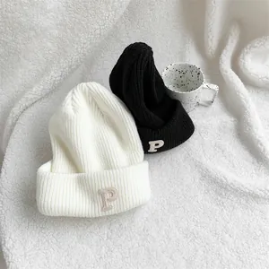 Pair of stylish knit beanies in black and white featuring letter P embroidery detail.