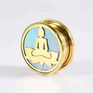Nahaufnahme von goldenem Edelstahl Ohr-Expander mit Buddha und Muschel-Hintergrund