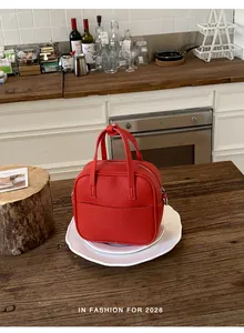 Detailansicht einer leuchtend roten quadratischen Lederhandtasche auf einem weißen Teller