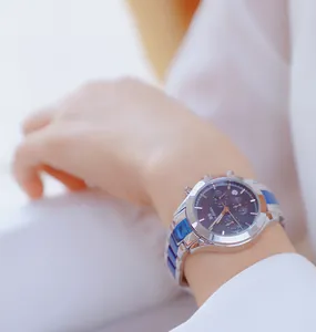 Primer plano de un elegante reloj cronógrafo de mujer con correa de acero azul y plata.