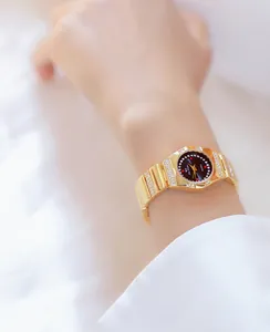 Detail van een luxueus goudkleurig dameshorloge met glinsterende strass-steentjes op de pols