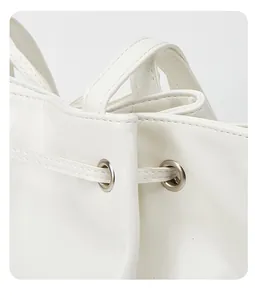 Detailansicht des Kordelzugverschlusses und der silbernen Ösen an einer weißen Tasche.
