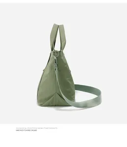 Vista laterale dettagliata di una grande borsa tote in nylon verde salvia con tracolla larga