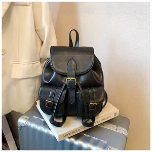 Mochila elegante de cuero negro con bolsillos múltiples sobre una maleta