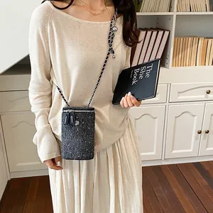 Elegant black tweed crossbody phone bag with metallic chain strap shown on a model outfit