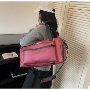 Large burgundy travel duffel bag with shoulder strap shown carried in a lifestyle setting