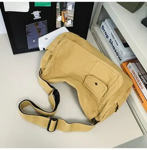 Close-up of a large yellow canvas messenger bag placed on a minimalist white desk.
