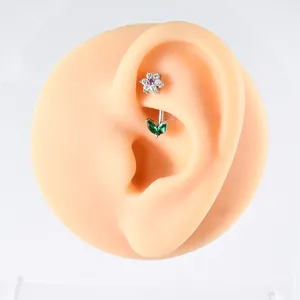 Detailed macro view of a curved stainless steel barbell with flower and green leaf zircons.