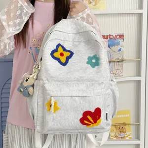 Close-up of a cute grey backpack with colorful flower embroidery and a bear charm