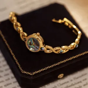 Primer plano de reloj vintage dorado con esfera de nácar sobre terciopelo negro