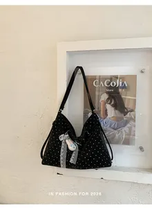 Fashionable black polka dot tote bag hanging on a white frame with charm detail