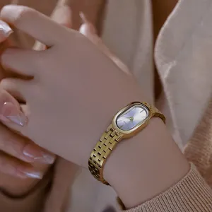 Detalle de un elegante reloj de acero inoxidable dorado en la muñeca de una mujer