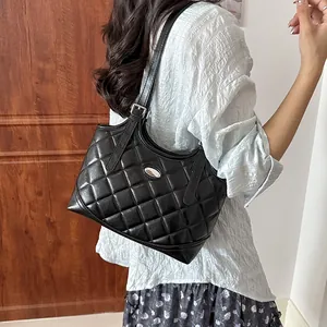 Elegante schwarze gesteppte Tragetasche am Model, zeigt stilvolle Rautenmuster-Texturdetails.