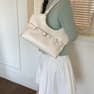 Close-up detail of a cream minimalist underarm tote bag with a decorative buckle strap.