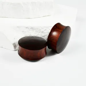 Detail view of polished red sandalwood waist drum ear plugs with natural wood grain texture