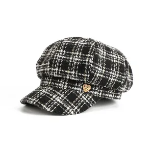 Close-up detail of a stylish black and white plaid newsboy hat with gold heart ornament
