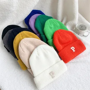 A collection of colorful knit beanies featuring embroidered P patch on textured white fabric