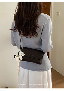 Vista posteriore di una borsa a tracolla marrone scuro con ciondolo a forma di cavallo