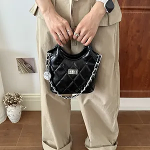 Detailed view of black quilted bucket bag with silver chain and charm detail.