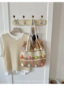Détail du sac cabas tissé main avec appliques de fleurs colorées dans un décor vintage.