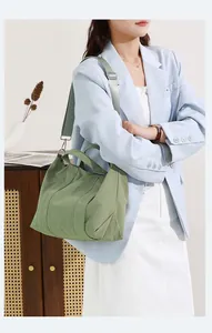 Dettaglio di una borsa tote in nylon verde indossata da una modella in stile casual.