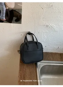 Detailaufnahme einer schwarzen Handtasche aus genarbtem Leder in rustikalem Ambiente.