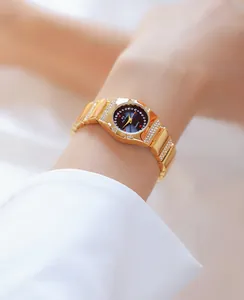Detailopname van een elegant gouden dameshorloge met strass-bezel en zwarte wijzerplaat