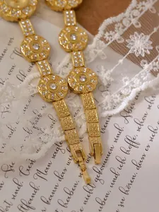 Close-up of vintage gold floral bracelet watch with crystal accents on a lace background