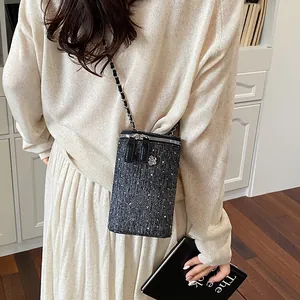 Model wearing a black tweed crossbody phone bag with chain strap and rhinestones