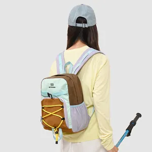 Detail eines bunten Wanderrucksacks, getragen von einem Modell mit Wanderstock.
