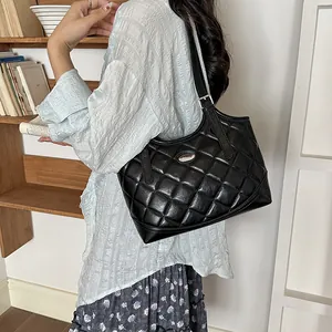 Model trägt eine schwarze gesteppte Leder-Einkaufstasche im klassischen Pendlerstil.