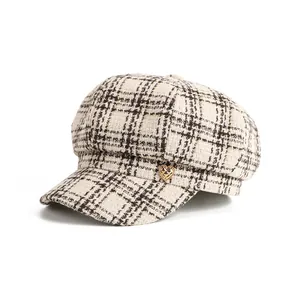 Detail view of the vintage plaid pattern and golden heart button on the newsboy hat.
