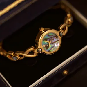 Primer plano de un reloj dorado vintage francés con esfera de concha de abulón iridiscente