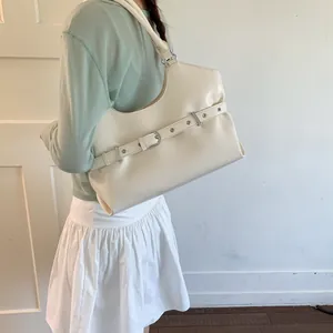 Detailed side view of a cream minimalist underarm tote bag with a decorative buckle strap.