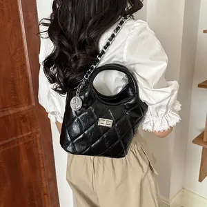 Back view of a woman wearing a black quilted bucket bag with silver chain strap