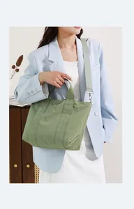 Vista dettagliata di una borsa tote in nylon verde salvia indossata da una modella.