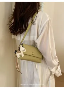 Elegante borsa sottobraccio verde chiaro con un'atmosfera retrò minimalista e ciondolo a cavallo