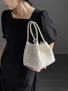 Close-up view of an elegant white hand-woven bucket bag being held by a model