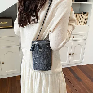Close-up of a tweed phone bag with a chain strap in a French-style chic outfit.