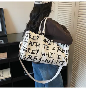 Detailed view of a fashionable large-capacity travel bag featuring bold black graffiti lettering.