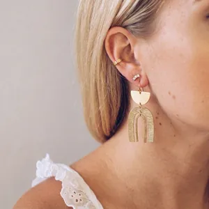 Gros plan détaillé de boucles d'oreilles dorées en forme d'arche au style bohème épuré