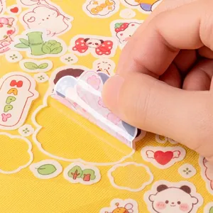 Close-up of hand peeling cute cartoon transparent PVC stickers for water bottles and journals